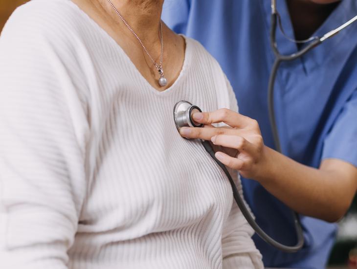 Een dokter luistert met een stethoscoop naar het hart van een patiënt.