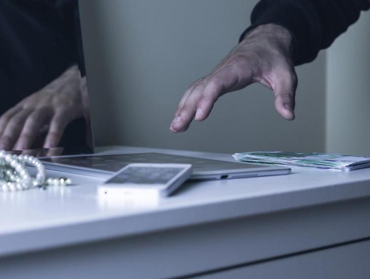 Een inbreker pakt kostbare spullen van een kastje