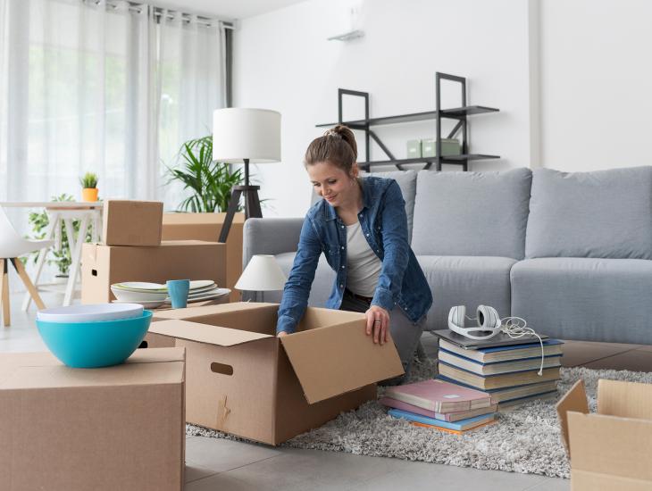Een vrouw is bezig met het inpakken van verhuisdozen.