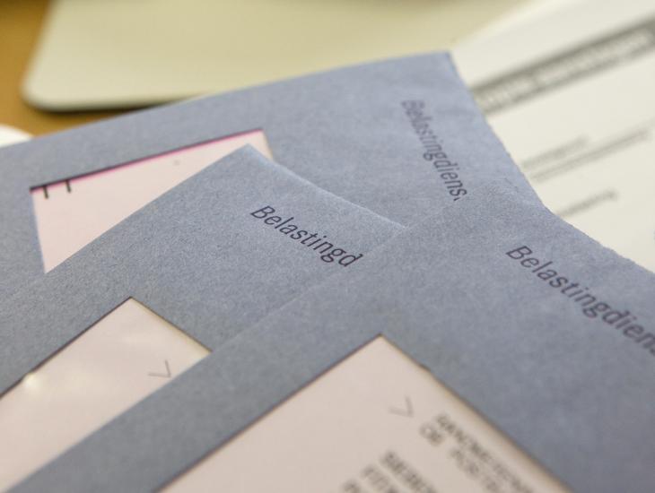 Drie blauwe belastingenveloppen liggen op tafel