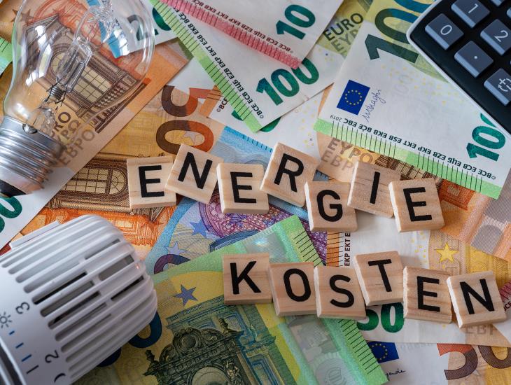 Een thermostaat, gloeilamp en een rekenmachine op een stapel euro-biljetten.