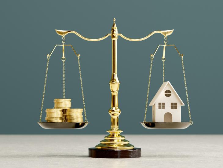 Een weegschaal met links een stapel muntgeld en rechts een huisje