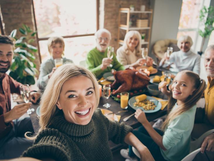 Een vrouw maakt een selfie van drie generaties die aan de eetkamertafel zitten