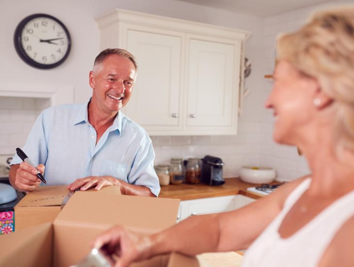 Een oude stel pakt na een verhuizing dozen uit in de keuekn van hun nieuwe woning.