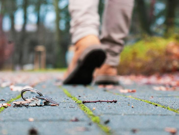 Een sleutelbos ligt op de stoep, op de achtergrond loopt een man weg.