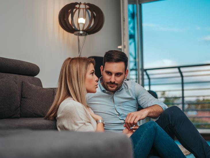 Jong stel zit op de grond, voor de bank, met elkaar te praten