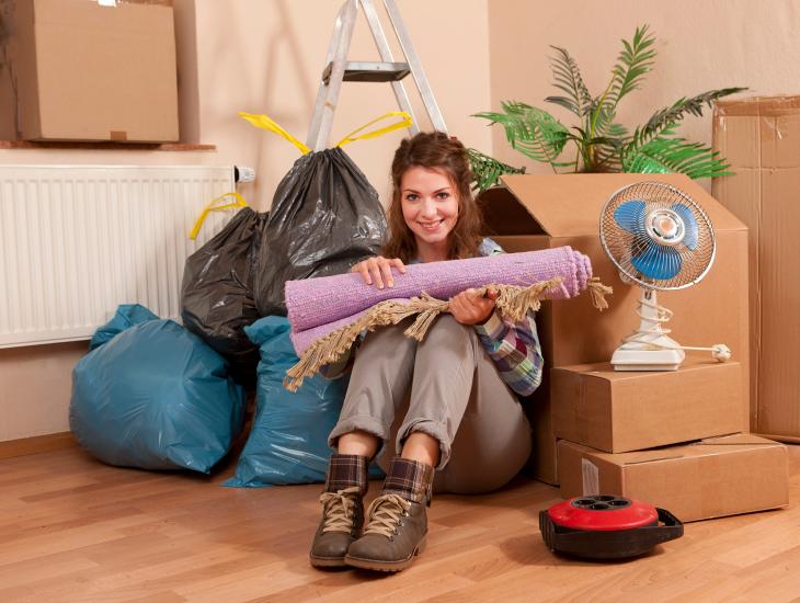 Een jonge vrouw die op zichzelf gaat wonen, zit tussen de verhuisdozen