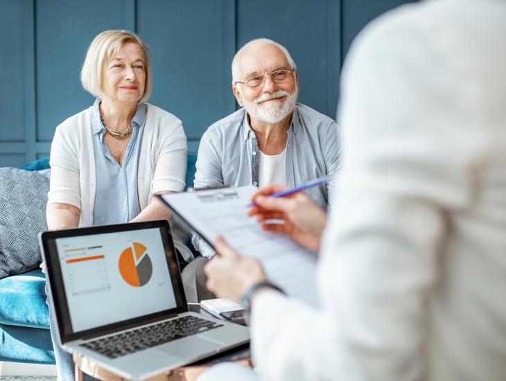 Een blij senior koppel is op bezoek bij hun Erkend Financieel Adviseur.