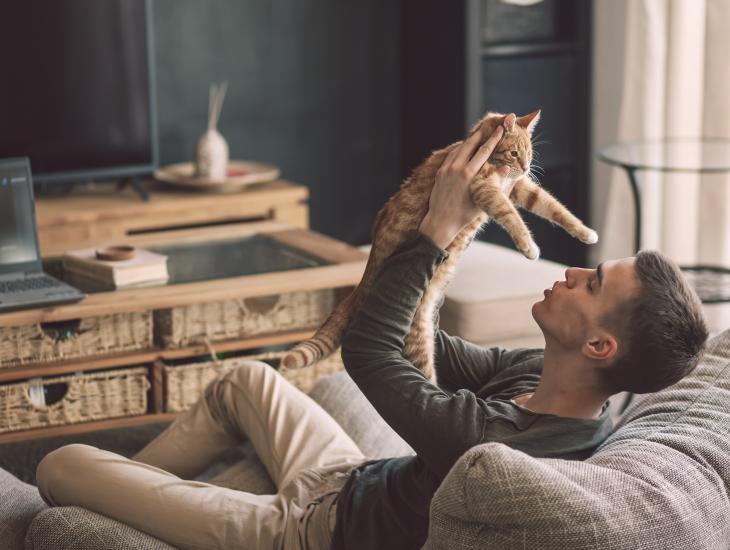 Een jonge man en zijn kat op de bank in de woonkamer.