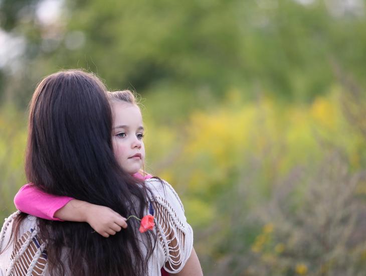 Jonge vrouw met kind op de arm, van achteren gezien