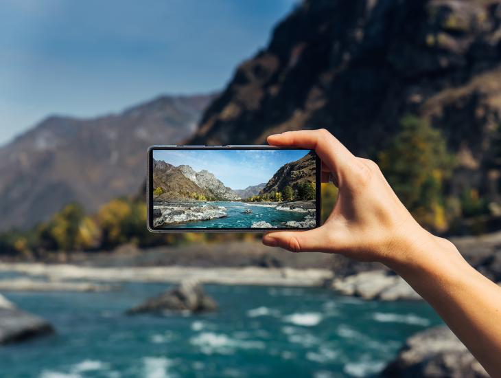 Iemand maakteen foto van een bergbeek met een mobiele telefoon.