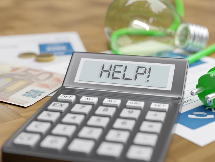 Een tafel met een stekker, euro-biljetten en een rekenmachine met daarop de tekst: Help!