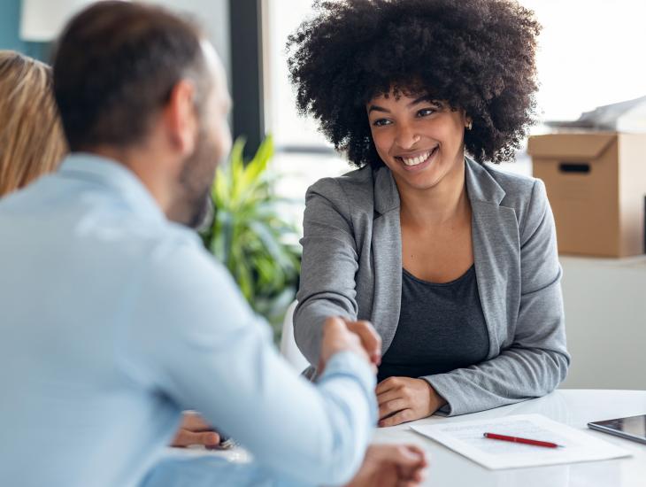 Makelaar feliciteert stel met de koop van hun huis.