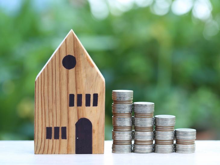 Huisje met stapeltjes munten ernaast, die steeds kleiner worden