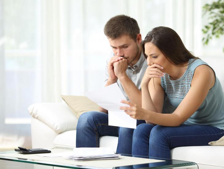 Jong stel, met bedrukte gezichten, leest op de bank een brief