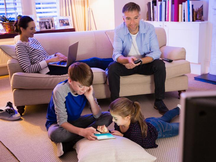 Vader, moeder en twee jonge kinderen in de huiskamer.
