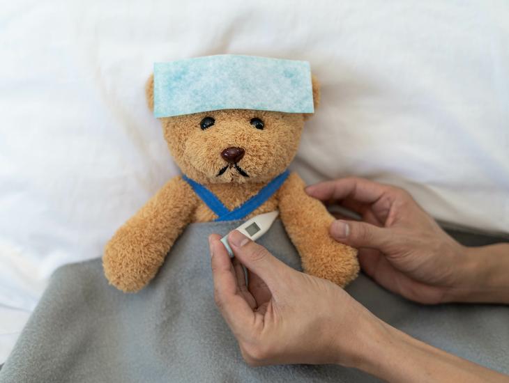 Iemand meet de temperatuur van een zieke knuffelbeer