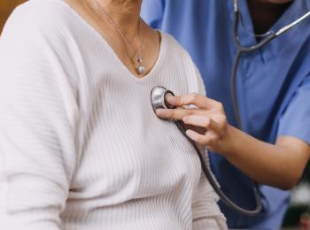 Een dokter luistert met een stethoscoop naar het hart van een patiënt.