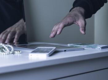 Een inbreker pakt kostbare spullen van een kastje