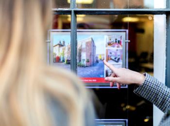 Een stel staat voor de etalage van een makelaar.