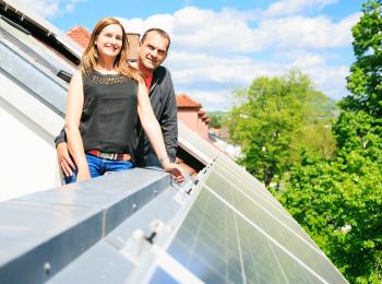 Een stel op het dak van hun huis, tussen de zonnepanelen.