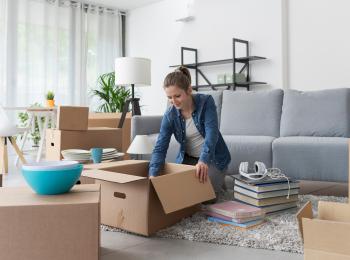 Een vrouw is bezig met het inpakken van verhuisdozen.