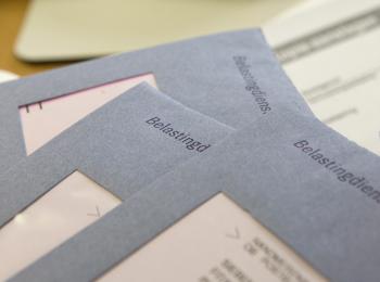 Drie blauwe belastingenveloppen liggen op tafel