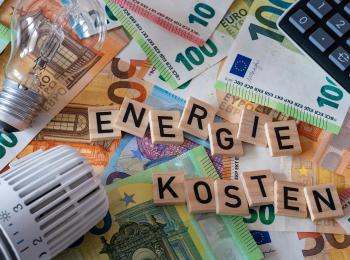 Een thermostaat, gloeilamp en een rekenmachine op een stapel euro-biljetten.