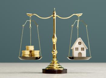 Een weegschaal met links een stapel muntgeld en rechts een huisje