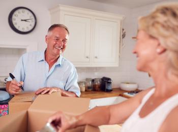 Een oude stel pakt na een verhuizing dozen uit in de keuekn van hun nieuwe woning.