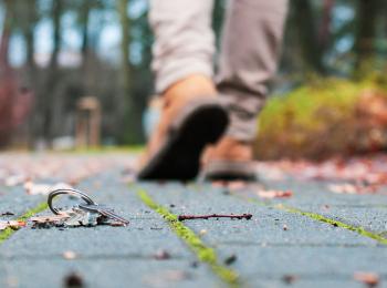 Een sleutelbos ligt op de stoep, op de achtergrond loopt een man weg.
