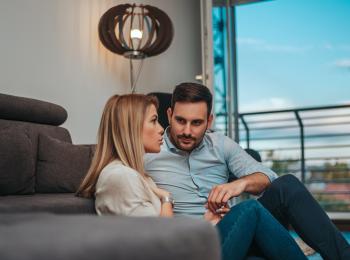 Jong stel zit op de grond, voor de bank, met elkaar te praten