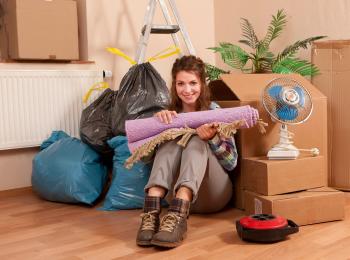 Een jonge vrouw die op zichzelf gaat wonen, zit tussen de verhuisdozen