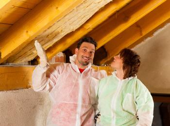 Een jong is het dak op zolder aan het isoleren.