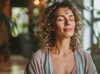Een opgeluchte vrouw zit met gesloten ogen in de huiskamer.