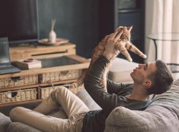 Een jonge man en zijn kat op de bank in de woonkamer.