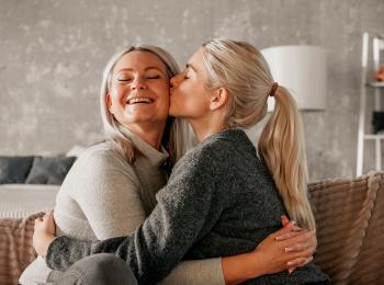 Een jonge vrouw geeft haar moeder een zoen