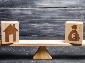 Weegschaal met een huis aan de ene kant en een zak geld aan de andere kant