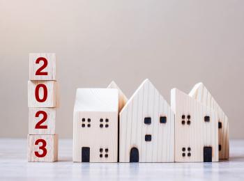 Het jaartal 2023 staat naast drie houten huisjes.