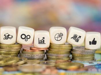 Stapeltje geld met daarop dobbelstenen 