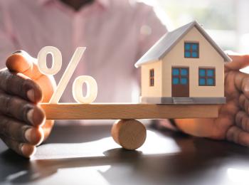 Een huisje en een procent-teken balanceren op een weegschaal