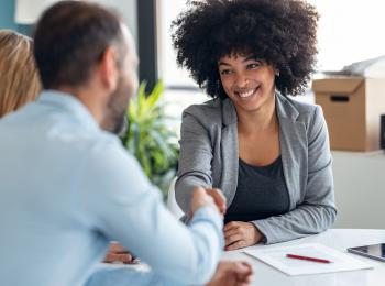Makelaar feliciteert stel met de koop van hun huis.