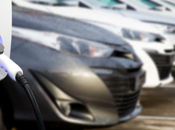 Laadpaal met elektrische auto's op de achtergrond