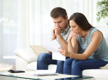 Jong stel, met bedrukte gezichten, leest op de bank een brief