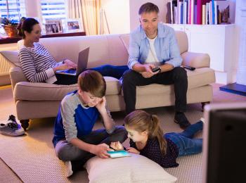 Vader, moeder en twee jonge kinderen in de huiskamer.