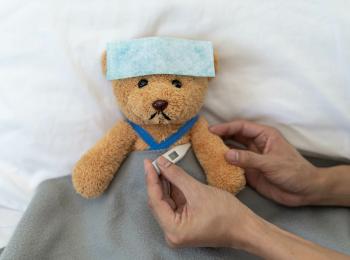 Iemand meet de temperatuur van een zieke knuffelbeer